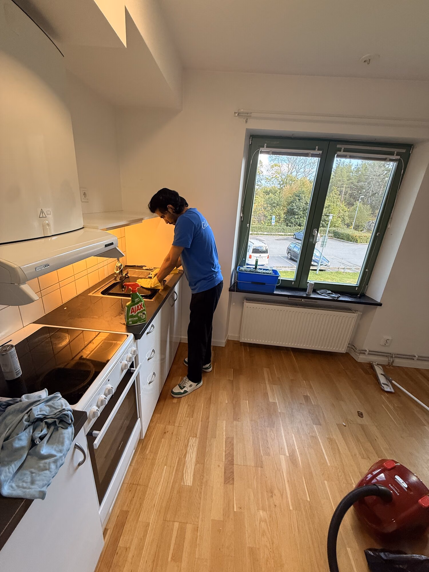 Städare i gula handskar rengör diskho och bänk i ett tomt kök