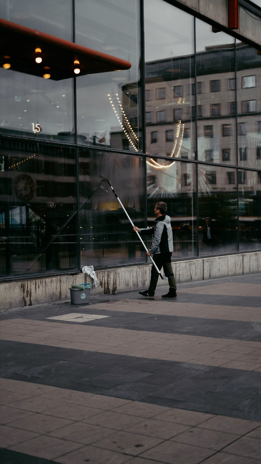Fönsterputsare med teleskopskaft rengör fönster på en fastighet