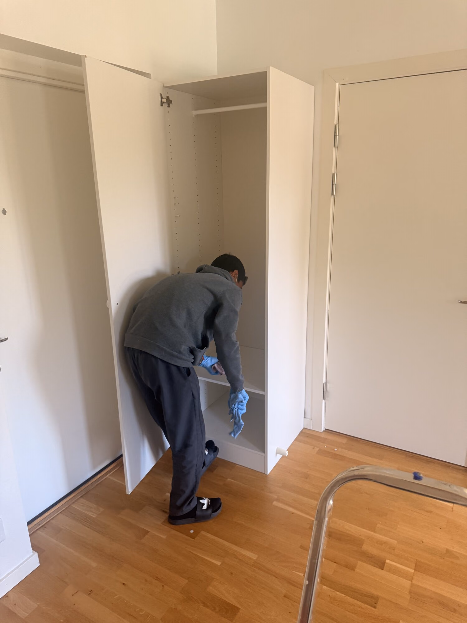 Städare med blå handskar torkar insidan av en tom garderob i en tömd lägenhet